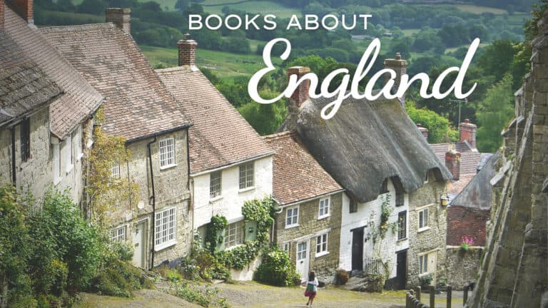 Scenic view of a quaint English village with stone cottages and thatched roofs nestled among green rolling hills. Overlaid text reads "BOOKS ABOUT England" in large white lettering, setting the theme for a collection of books about england.