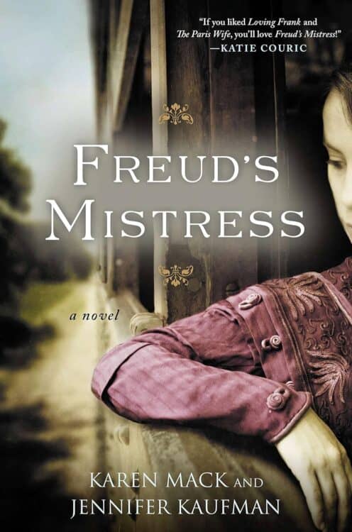 Cover of Freud’s Mistress, a novel by Karen Mack and Jennifer Kaufman, showing a sepia-toned image of a woman in a deep burgundy embroidered dress leaning pensively against a wooden surface. A quote from Katie Couric at the top compares the book to Loving Frank and The Paris Wife.