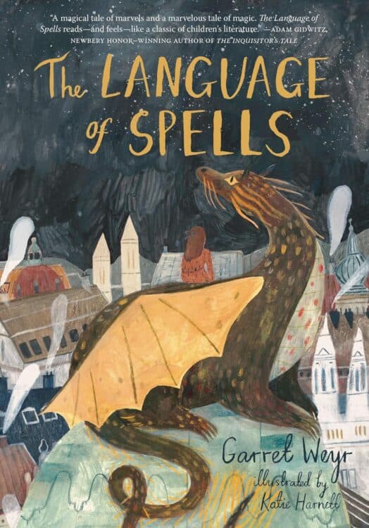 Cover of The Language of Spells by Garret Weyr, illustrated by Katie Harnett, featuring a large dragon with golden-yellow wings perched above a whimsical, old-world town at night. A young girl sits beside the dragon, both gazing out into the starry sky, evoking a magical and contemplative mood. The cover includes a quote praising the book as a classic-feeling tale of magic and marvels.
