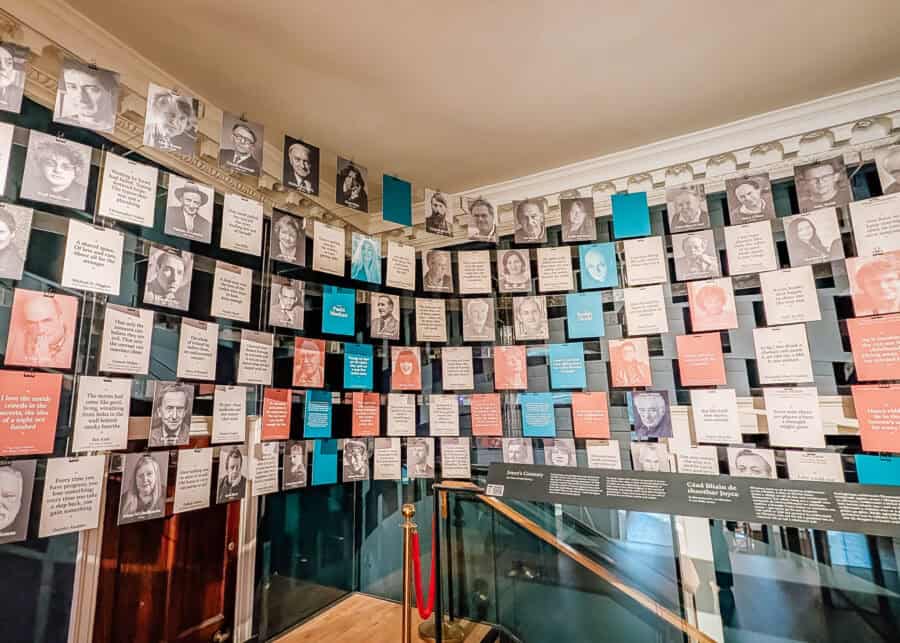 Literary display wall at the Museum of Literature Ireland (MoLI) in Dublin featuring portraits and quotes from Irish writers and public figures. Panels of various colors are arranged in a grid above a staircase, celebrating the country's rich storytelling heritage.