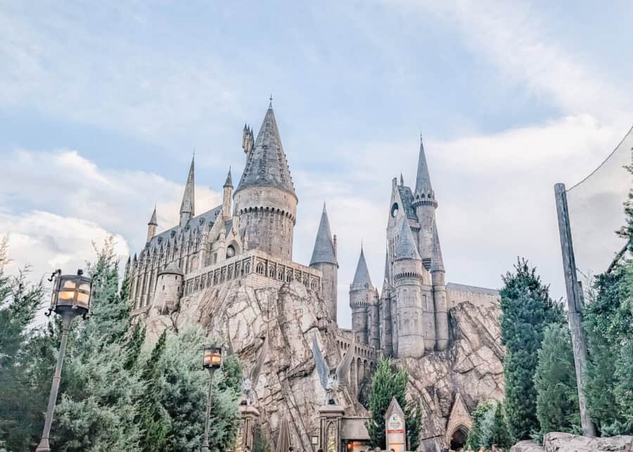 Hogwarts Castle rises atop rocky cliffs in The Wizarding World of Harry Potter at Universal Orlando, with tall stone towers and spires overlooking the entrance path below.