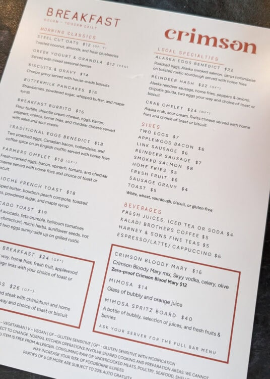 Breakfast menu for Crimson restaurant listing morning classics. Local specialties. Sides. Beverages. Crimson Bloody Mary. Mimosa. And Mimosa Spritz Board. Menu items include steel cut oats. Greek yogurt and granola. Biscuits and gravy. Buttermilk pancakes. Breakfast burrito. Traditional eggs Benedict. Farmers omelet. Brioche French toast. Avocado toast. Alaska eggs Benedict. Reindeer hash. Crab omelet. Eggs. Applewood bacon. Link sausage. Reindeer sausage. Smoked salmon. Home fries. Fresh fruit. Sausage gravy. Toast. Fresh juices. Iced tea. Soda. Kaladi Brothers coffee. Harney and Sons fine teas. Espresso. Latte. And cappuccino.